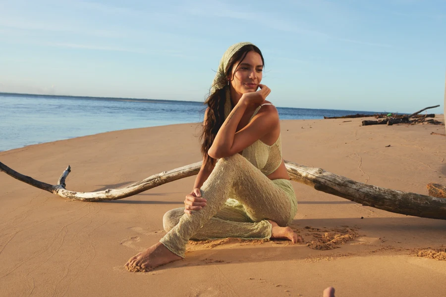 Modelo à beira-mar, sentada em um tronco na areia